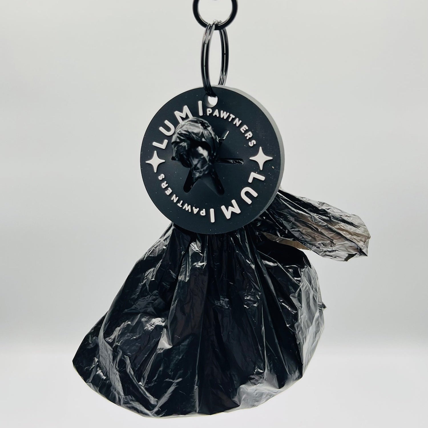 Black plastic bag with a poop loop labeled 'Lumi Pawther' on a white background